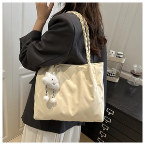 Close-up of cream tote bag with quilted texture, braided strap and cloud charm