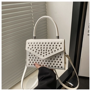 Close-up of white PU leather handbag featuring silver studs and V-shaped flap cover