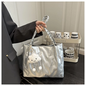 Detail of silver quilted tote bag with woven handles and a cute plush cloud charm