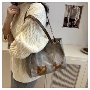 Detail of grey canvas tote bag with brown leather strap and chain on a white background