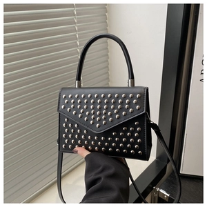 Detail of black envelope bag featuring silver V-shaped studs and round handle