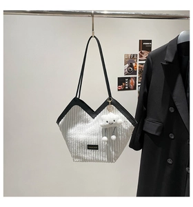 Detailed shot of white corduroy tote bag with black contrast trim and cloud charm