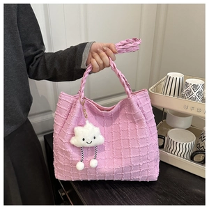 Detailed view of pink woven tote bag featuring a cute white cloud plush charm and handle