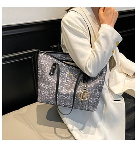 Dettaglio della grande borsa tote intrecciata con motivo pixel e ciondolo dorato M