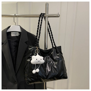 Detail of black quilted tote bag with twisted straps and a cute cloud charm hanging