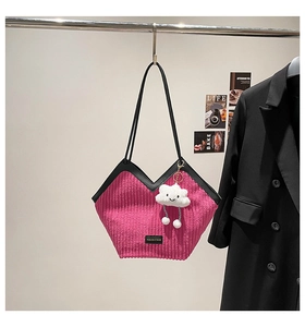 Detail of pink corduroy tote bag with black trim, logo patch and smiley cloud charm