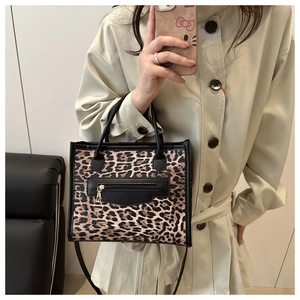 Detail of leopard print tote bag with black leather zip pocket and sturdy handles