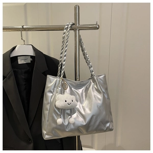 Detail of silver metallic tote bag with pleated texture and white cloud plush pendant