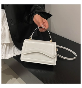 Close-up of white PU leather crossbody bag featuring unique wavy embossed pattern and gold hardware