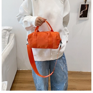 Detail of a vibrant orange nylon cylindrical crossbody bag with sports styling