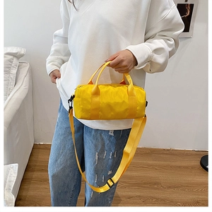 Close-up of a vibrant yellow waterproof nylon cylinder bag with shoulder straps