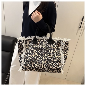 Detail of large leopard print tote bag with white fringe trim and black handles