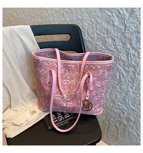 Dettaglio della borsa tote rosa intrecciata con logo ZHEI BAG e ciondolo a M