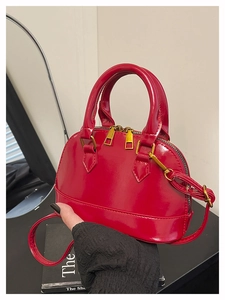 Detailed macro view of red patent leather shell bag with golden zipper and handles