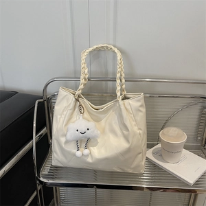 Beige pleated tote bag with woven handles and fluffy cloud charm on modern glass shelf
