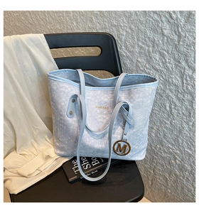Dettaglio della borsa tote azzurra con logo dorato ZIMEIBAG e ciondolo a lettera M