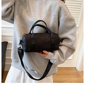 Detail of a black nylon barrel bag with adjustable strap and smooth texture