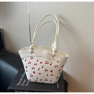 Detailed close-up of white PU leather bucket bag featuring cute red cherry prints