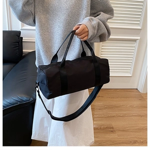 Detail of a black cylindrical sports bag showing nylon texture and adjustable shoulder strap