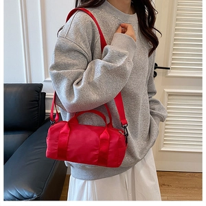 Red nylon barrel bag with black hardware shown on model for daily casual outfit style