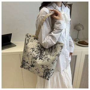 Close-up of ink-wash bamboo print tote bag on a minimalist desk with laptop and decor