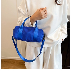 Vibrant blue nylon cylinder bag worn with casual outfit showing large capacity