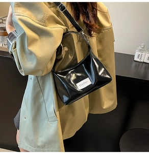 Detail of black patent leather cloud bag featuring branded label and glossy finish