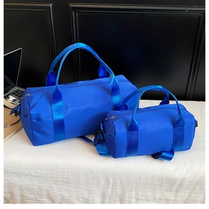 Detailed comparison of large and small blue nylon duffel bags on white textured fabric