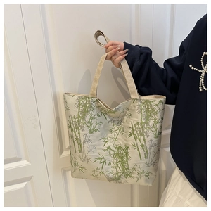 Detail of canvas tote bag featuring green bamboo ink print and dual shoulder straps