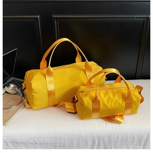 Detail of yellow nylon cylinder duffel bags with adjustable straps and black hardware