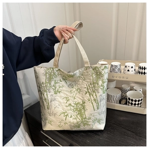 Detail of canvas tote bag featuring green bamboo print and durable shoulder straps