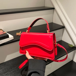 Modern red glossy leather handbag with wavy flap and adjustable shoulder strap for women