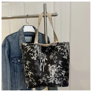 Detail of black canvas tote bag with white bamboo print and thick beige fabric handle