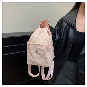 Detail of light pink nylon mini backpack featuring a metal magnetic buckle and textured fabric