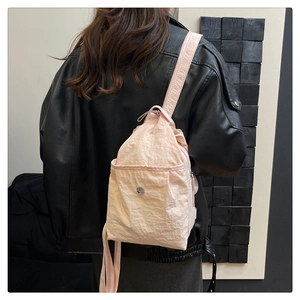 Rear view of a model wearing a pink nylon backpack with black leather jacket