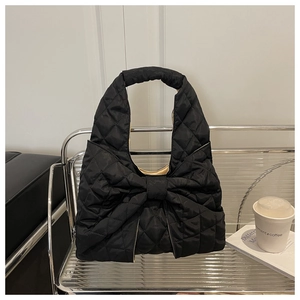 Detail of black quilted tote bag featuring a large bow and classic diamond stitching
