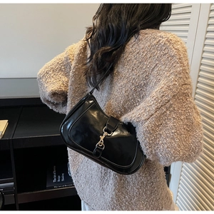 Détail du sac à bandoulière noir brillant avec fermoir doré sur fond d'intérieur moderne