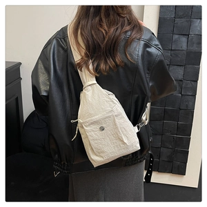 Detail der beigefarbenen Nylon-Brusttasche mit Magnetfach über einer schwarzen Lederjacke