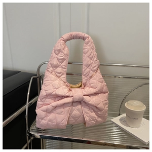 Close-up of pink quilted nylon tote bag featuring a large decorative bow on a metal shelf