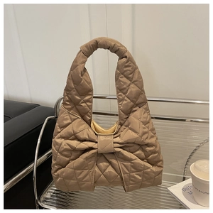 Close-up of khaki quilted tote bag with large bow detail on a stylish display