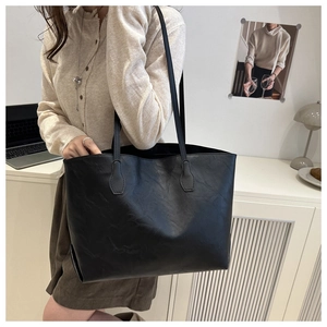 Minimalist large black tote bag in matte leather shown in a stylish lifestyle office setting