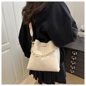 Close-up of cream lychee texture leather bucket bag with resin chain handle and strap