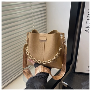 Close-up of khaki leather bucket bag with chunky chain handle and woven shoulder strap