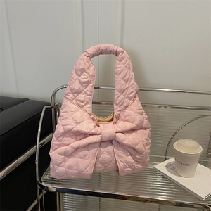 Pink quilted hobo tote bag with a large decorative bow and diamond stitched pattern