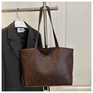 Detail of vintage brown tote bag with textured leather finish and long shoulder straps