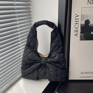 Quilted black puffer tote bag featuring a large bow design and spacious interior