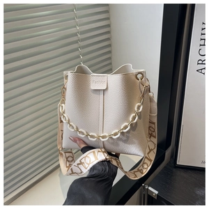 Close-up of white lychee texture bucket bag with gold chain and wide printed strap