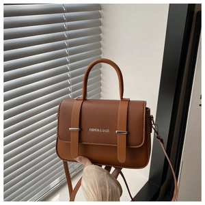 Close-up of retro brown pebbled leather crossbody bag with buckle detail and handle