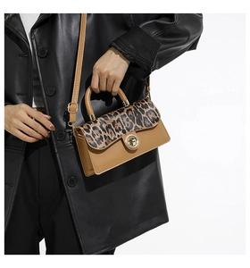 Detail der Klappe mit Leopardenmuster und goldenem Drehverschluss an brauner Tasche