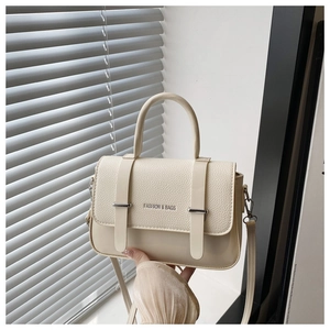 Detail of beige faux leather handbag featuring litchi texture and metal buckle closure